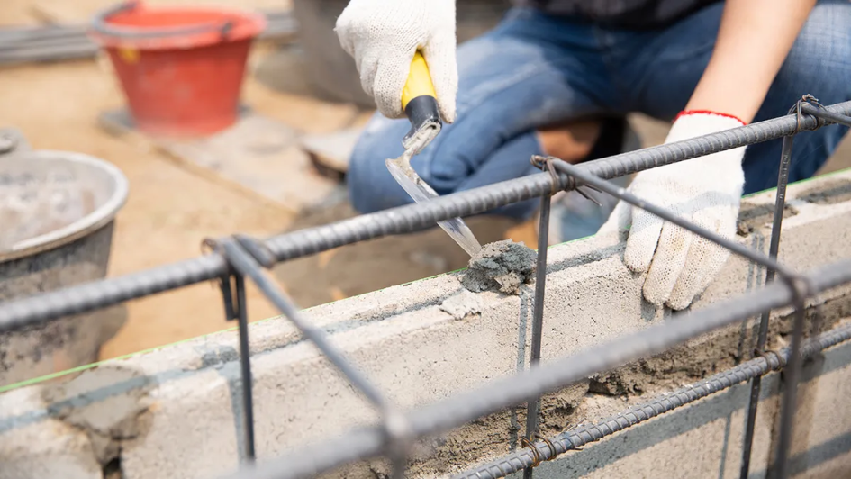 IGTSS resolvió períodos de licencia en la industria de la construcción Manos de obrero trabajando con cemento