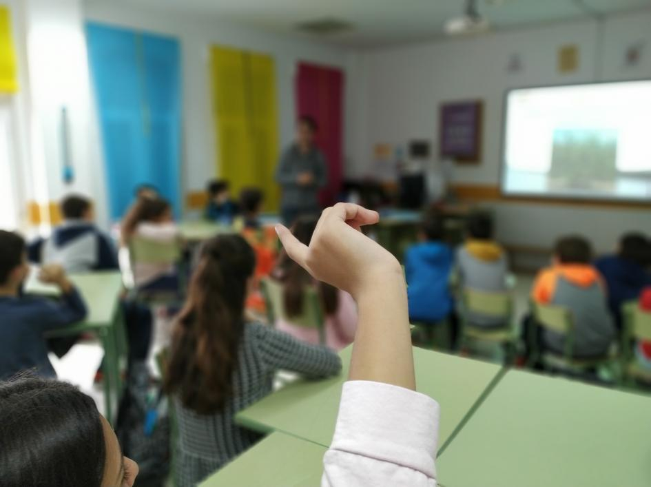 Alumno levantando la mano en un salón de clase
