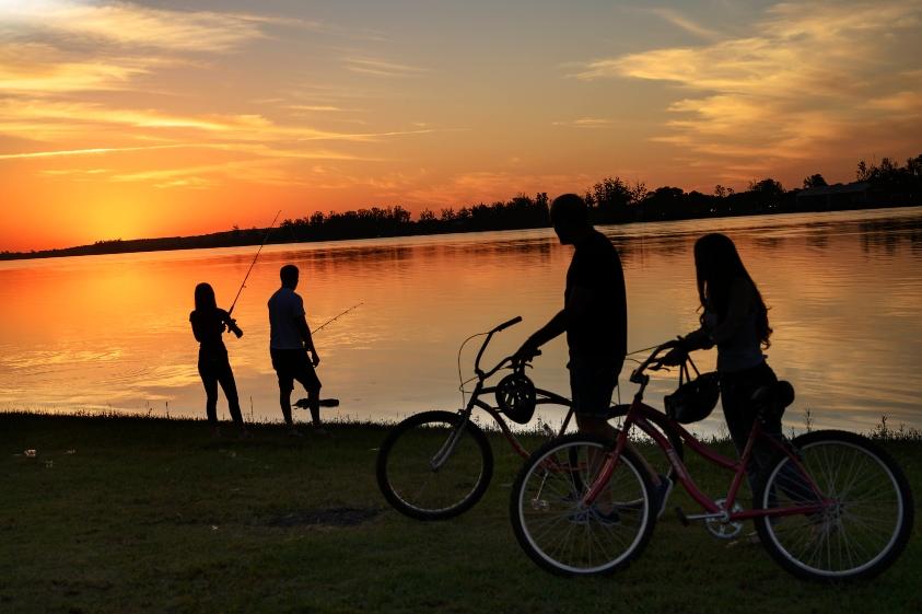 Atardecer en el lago con gente pescado y una pareja con sus bicicletas