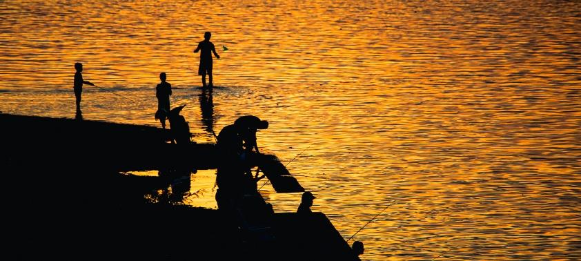 Personas pescando en un atardecer junto al río en Salto