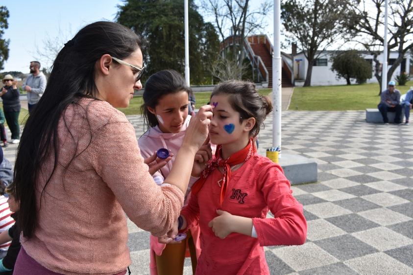 Dos niñas y una recreadora pintandole la cara a una de las usuarias de la Colonia Raigón del BPS 