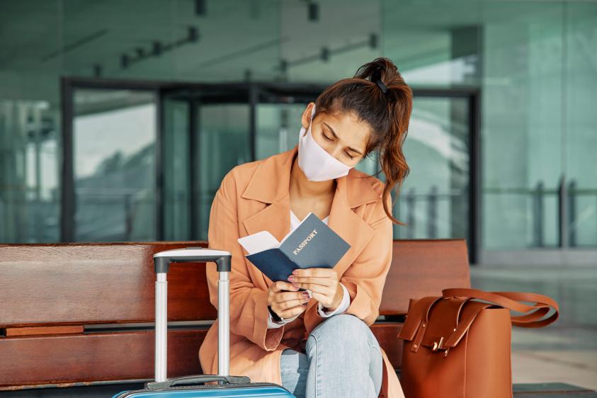 Pasajera con tapabocas revisa su pasaporte en aeropuerto durante la pandemia Pasajera con tapabocas revisa su pasaporte en aeropuerto durante la pandemia