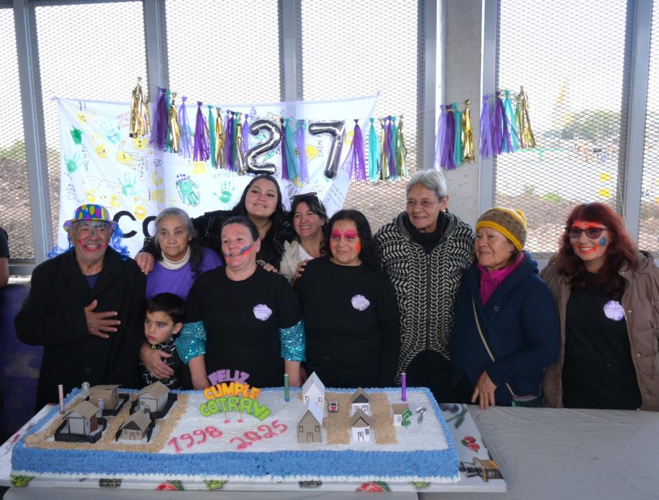 Vecinos abrazados detrás de la torta 27 aniversario del Barrio Cotravi
