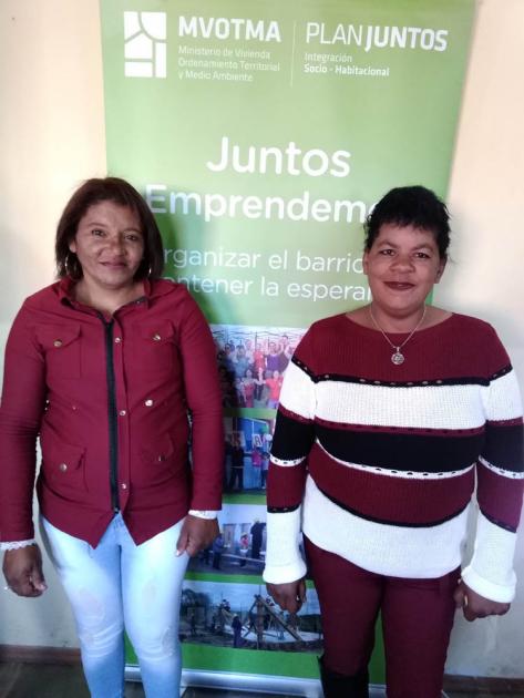 8 familias dos mujeres junto a un cartel de Mvotma