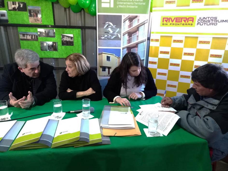 8 familias Eneida de leon junto a 2 autoridades y un señor firmando la documentación de su vivienda