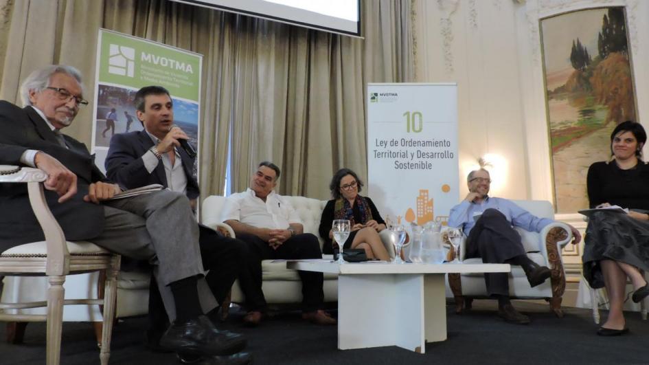 Imagen del living integrado por Arana, García, Vidalín, Ayala, Arím y la gerenta de la Dinot Verónica Pastore. Garía está haciendo su exposición 