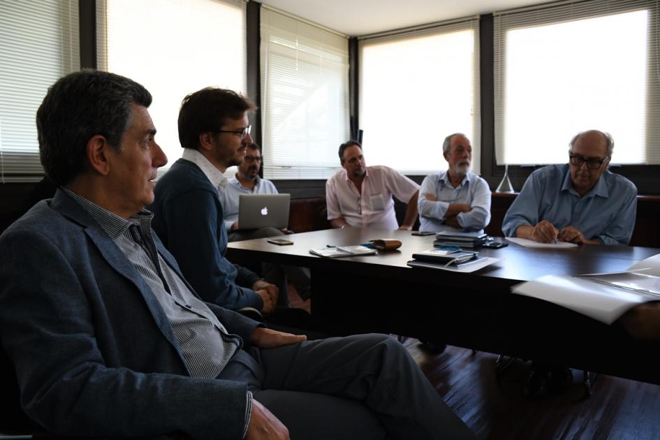Sala de reuniones con representantes de ASSE y Dinot, autoridades y equipos técnicos de ambas instituciones sentados alrededor de una mesa dialogando