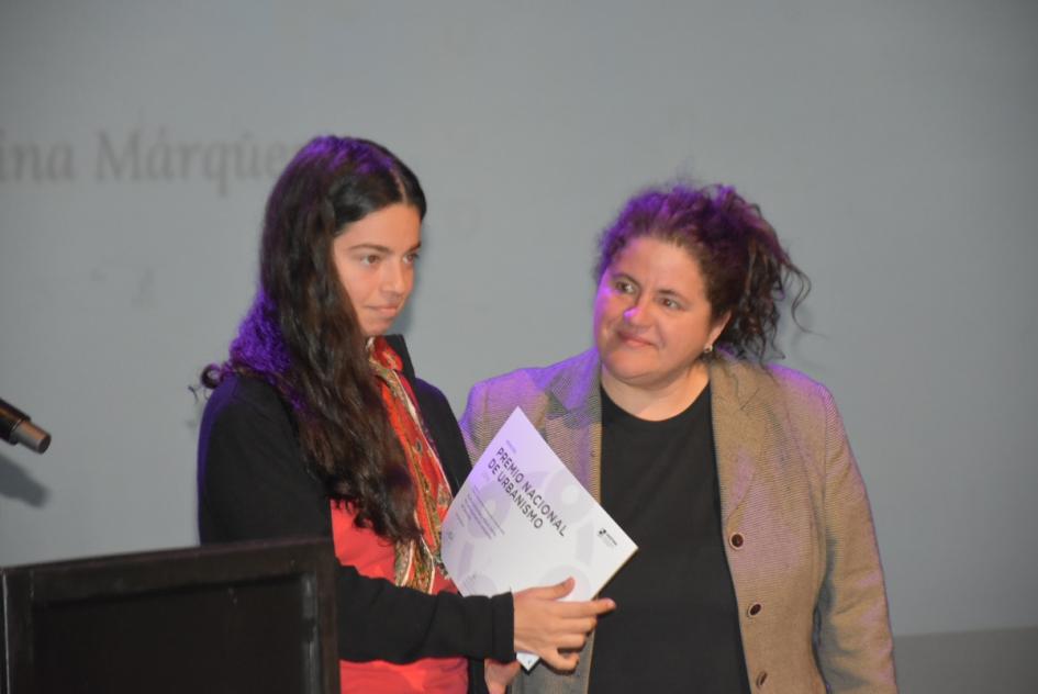 Una de las miembros del jurado entregando premio a una de las ganadoras en el escenario 