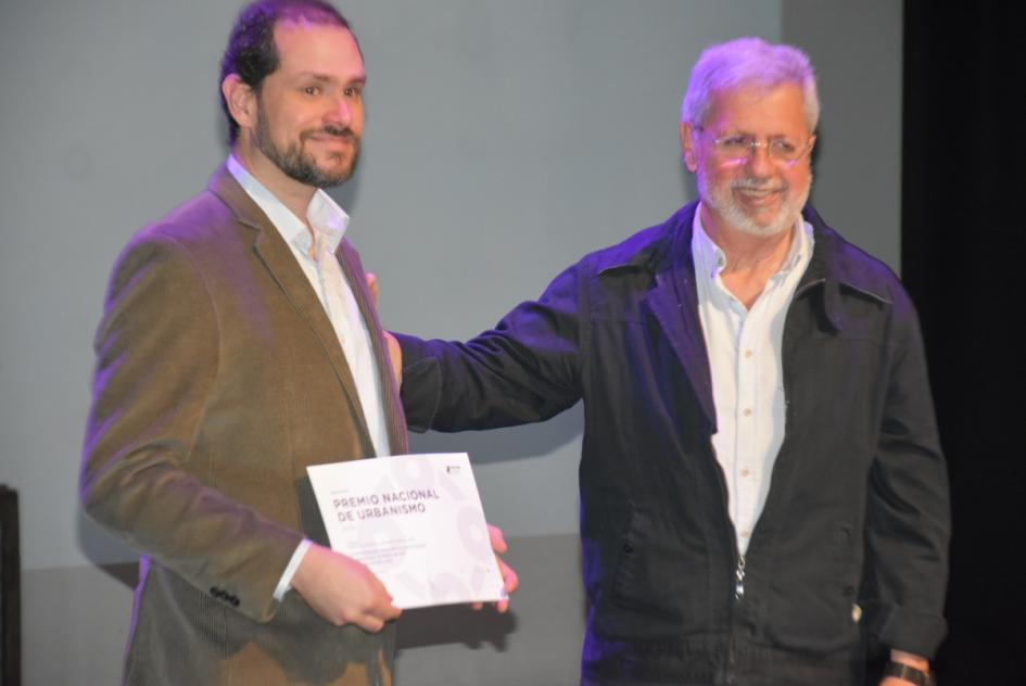 Miembro del jurado entregando premio a una de los ganadores en el escenario 