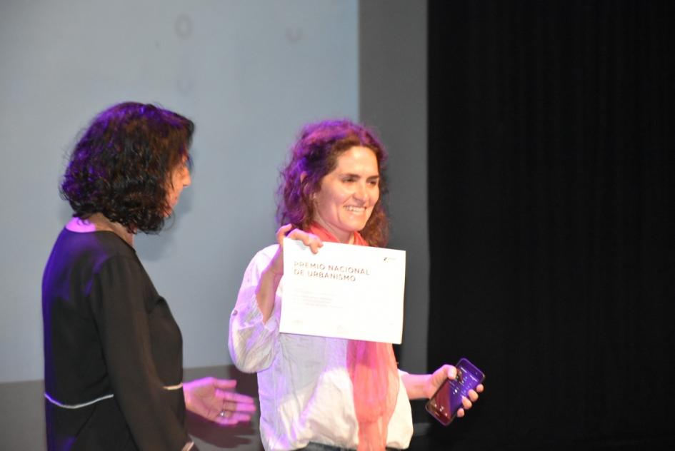 Otra de las miembros del jurado entregando premio a representante de la ganadora del premio 