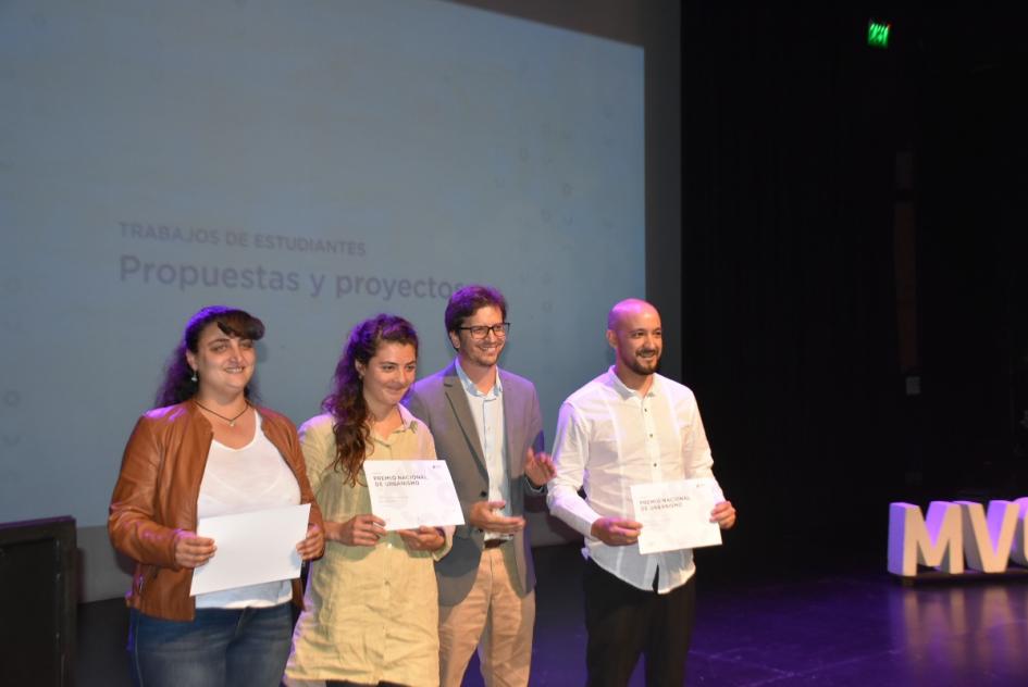 el director nacional José Freitas posando junto a ganadores para la cámara en el escenario, luego de entregarles el certificado