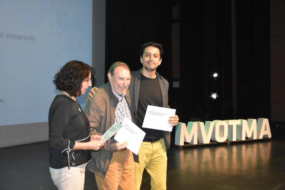 Una de las miembros del jurado con dos de los ganadores del Premio en el escenario al momento de la entrega 