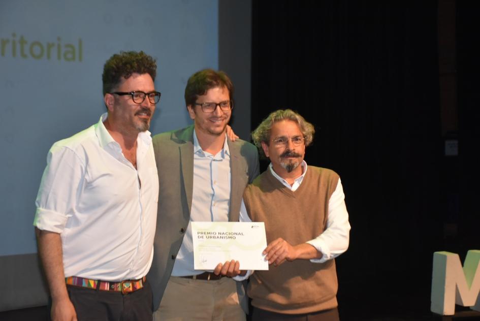 El director Freitas posa para la foto junto a dos de los ganadores en el escenario 