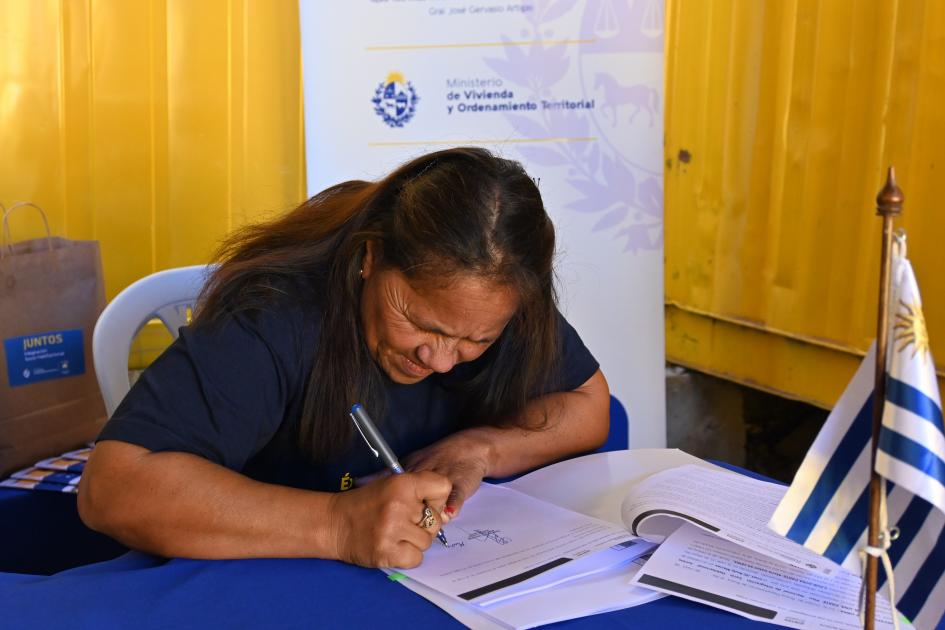 Participante de Juntos firma los documentos de su nueva vivienda