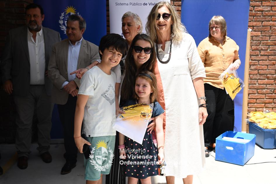 Entrega de llaves a familia Feliz familia posando junto a funcionaria con la llave de su nueva vivienda