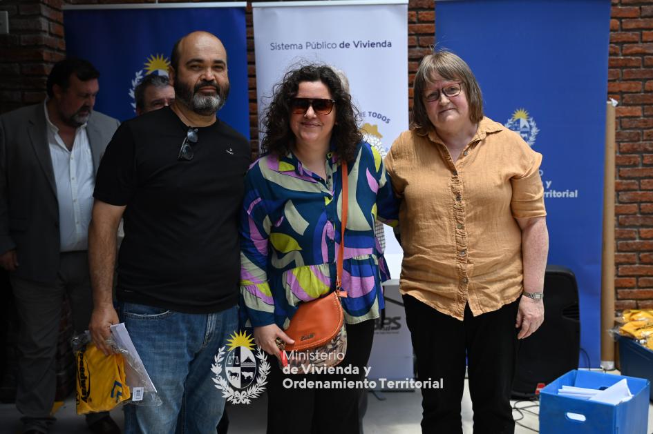 Pareja de nuevos propietarios Feliz pareja posando junto a funcionaria después de haber recibido las llaves de su nueva vivienda