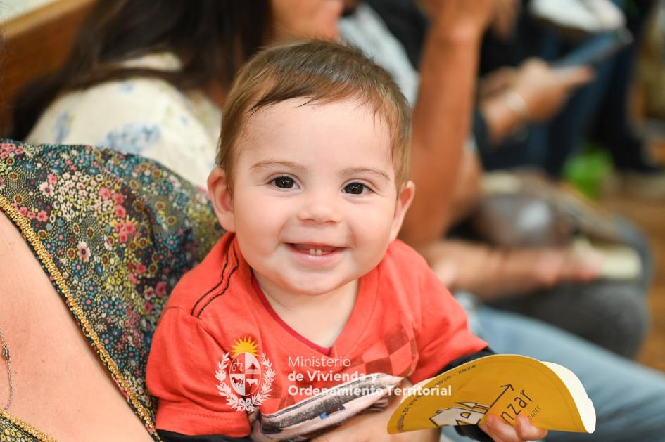 Niño en la entrega de viviendas en Mercedes Niño pequeño mirando a la cámara felizmente mientras sostiene un sticker del Plan Avanzar