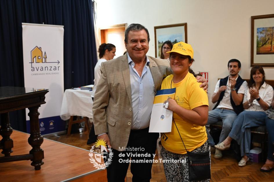 Ministro sonriendo junto a vecina emocionada por tener las llaves de su nueva casa