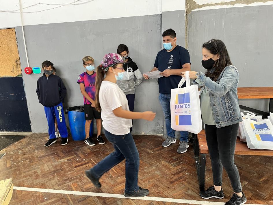 Entrega de kits conteniendo gorra para piscina, toalla y ojotas