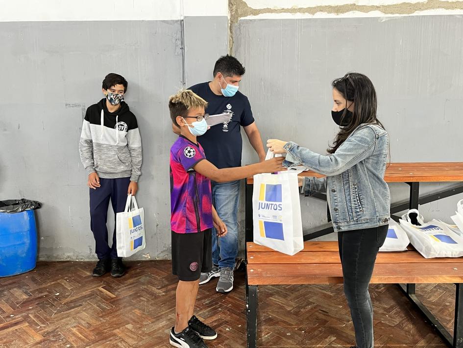 Entrega de kits conteniendo gorra para piscina, toalla y ojotas
