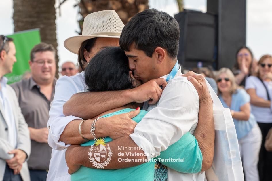 Familia emocionada en el evento de Mevir Hijo abrazando y besando a su madre en la entrega de llaves de las viviendas