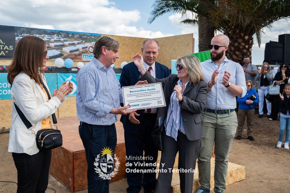 Presidente de Mevir y Subsecretario entregando placa del complejo de viviendas a familia 