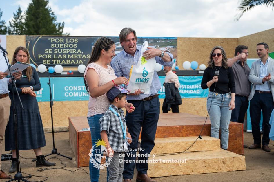 Presidente de Mevir junto a familia Presidente de Mevir sonriendo mientras entrega insumos y llaves a familia