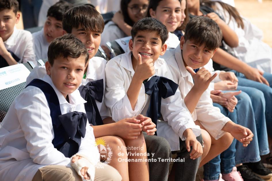 Chicos de escuela sonriendo y posando para la foto en el evento de Mevir