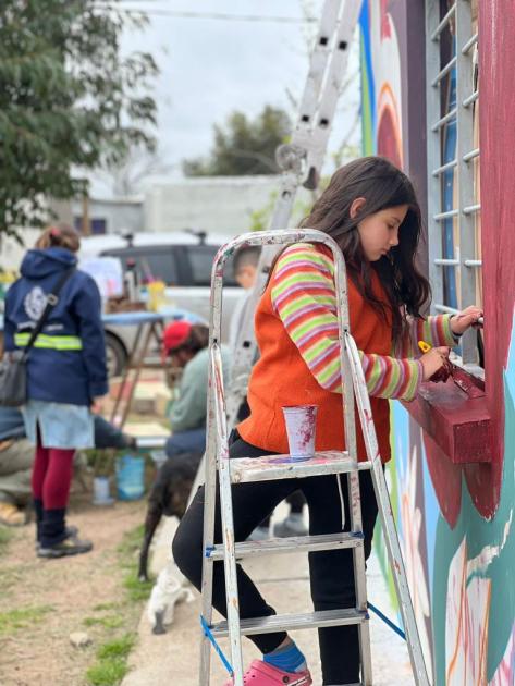 La familia del barrio ayudando a pintar el mural