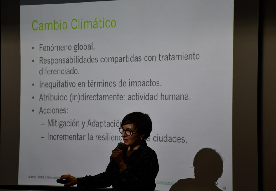 Jornada de formación Una de las expositoras con micrófono dando una charla. Al fondo una pantalla proyectada