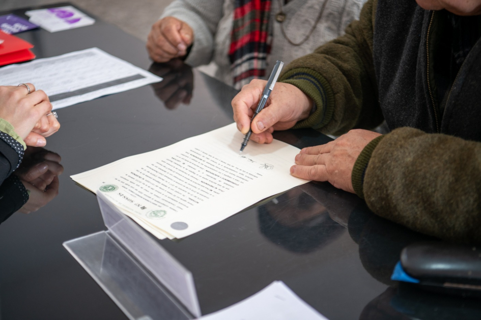 Titulaciones El Tanque - Villa Prosperidad primer plano de manos firmando un título de propiedad