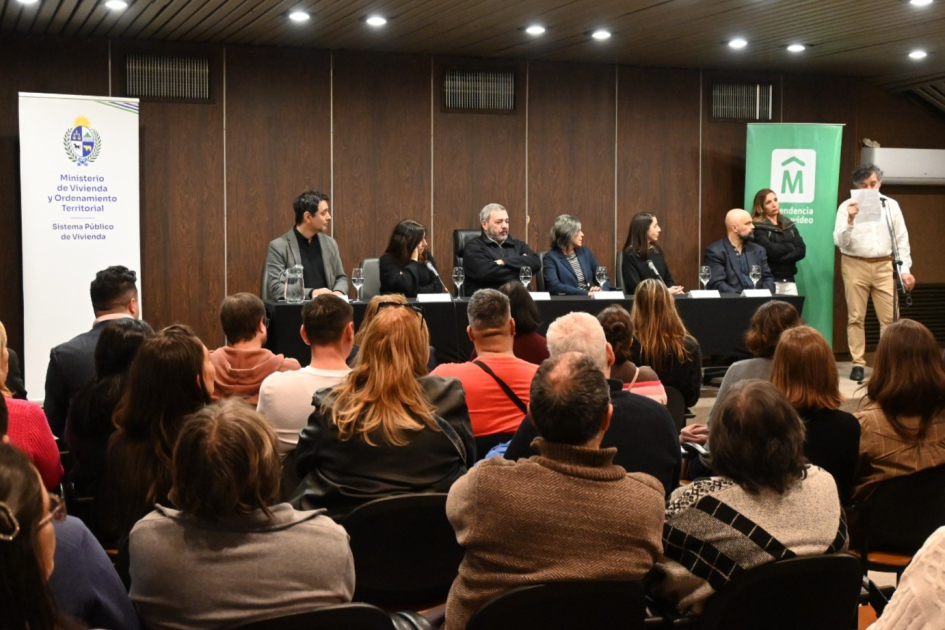 Titulaciones El Tanque - Villa Prosperidad autoridades MVOT y IM en mesa al fondo frente al público y vecino de pie diciendo unas palabras