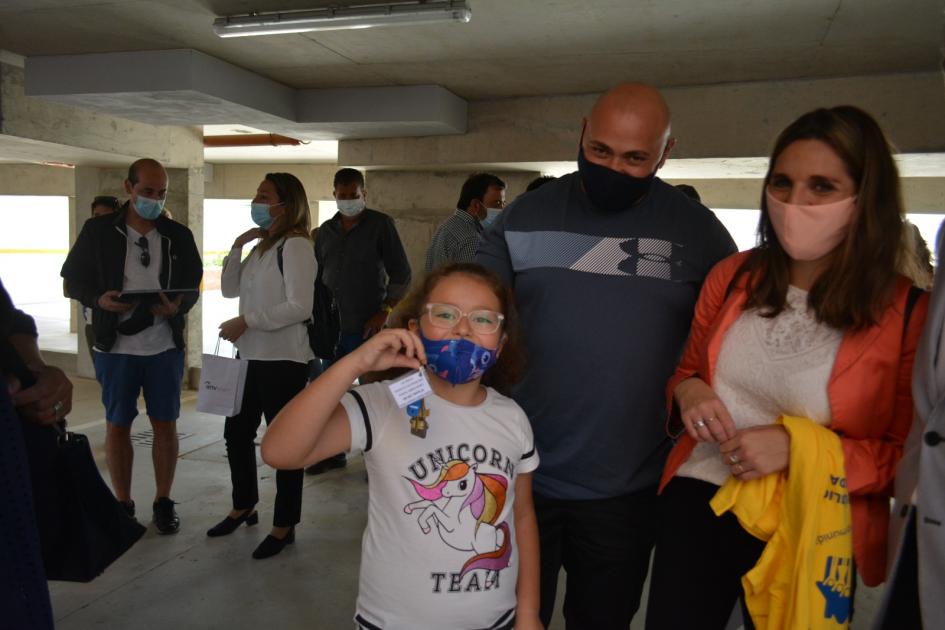 Niña sosteniendo la llave de su nueva vivienda junto a sus padres