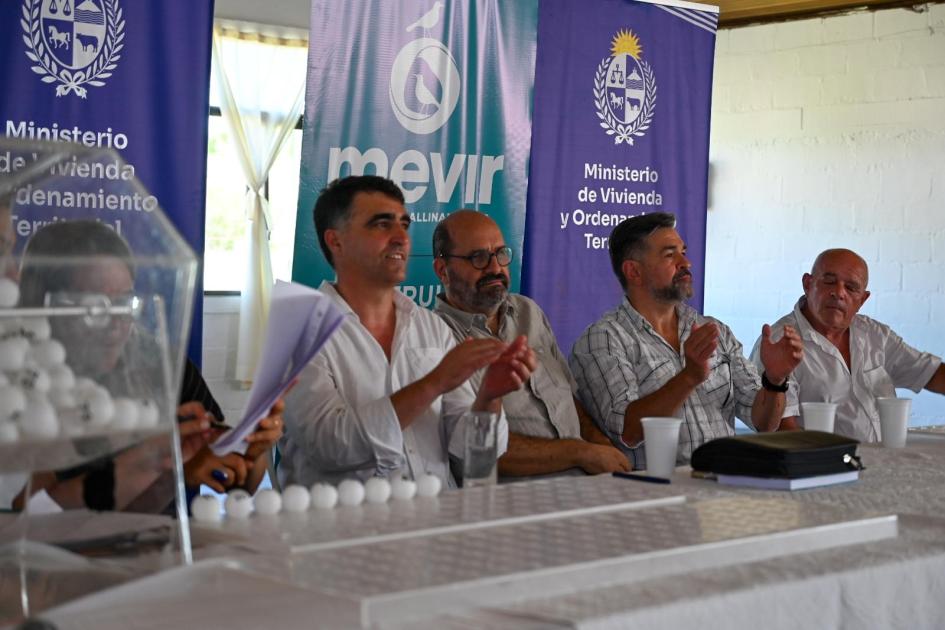 Sorteo Mevir - Los Cerrillos Autoridades de Mevir sentadas en la mesa junto a la escribana mientras se realiza el sorteo