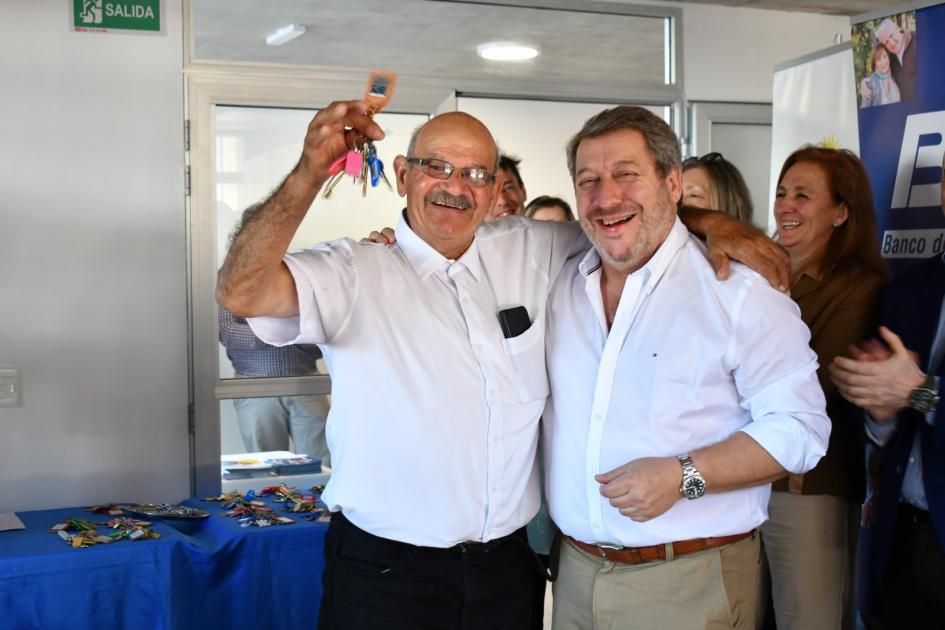 vecino y presidente del BPS juntos beneficiario feliz con llave en mano abrazado al presidente de BPS