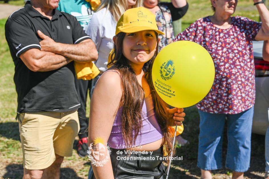 Niña presente en la entrega de viviendas Niña sonriente usando un gorro del ministerio mientras sostiene un globo también del ministerio