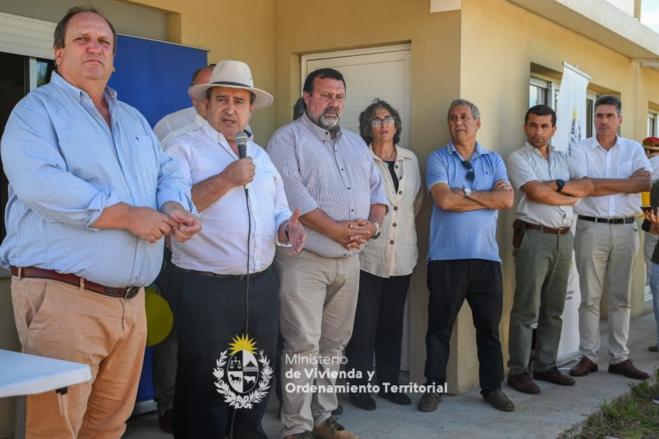 Ministro hablando por el micrófono a la gente que vino a la entrega de viviendas con las autoridades 