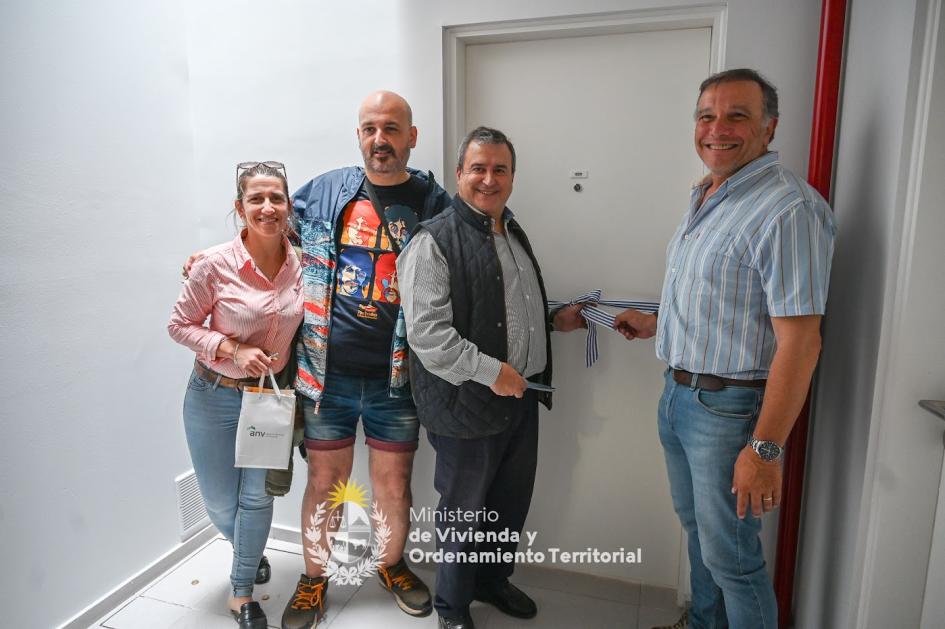 Inauguración de la vivienda Ministro de vivienda e Intendente junto a una familia en la puerta de su nuevo hogar