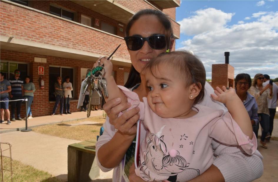 Inauguración salto Madre carga a un bebe que tiene la llave de una vivienda