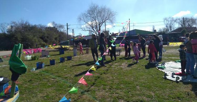 Fiesta infantil en barrio Lavalleja Varios niños jugando con banderines en forma de triangulos de varios colores
