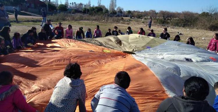 Fiesta infantil en barrio Lavalleja Varias personas sosteniendo una tela en forma de circulo grande con varios colores