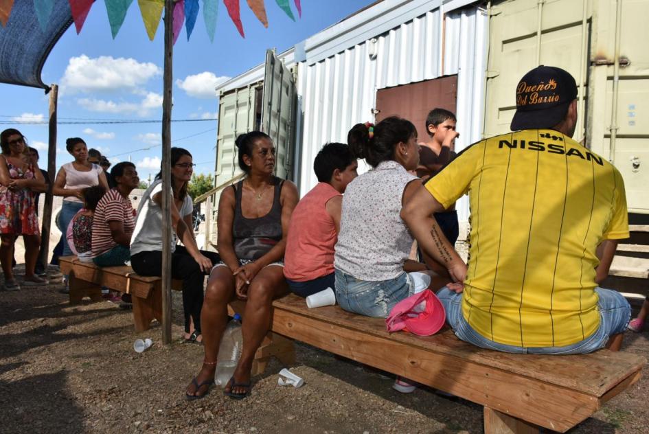 Plan juntos Varias familias sentadas frente a una vivienda