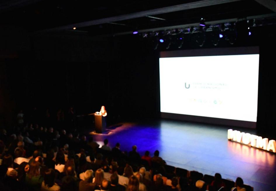 Se ve a la presentadora del Premio en la apertura. En el escenario de la sala Hubo Balzo, donde se encuentra una pantalla gigante con la estética del premio, un corpóreo del Mvotma y parte del público presente 