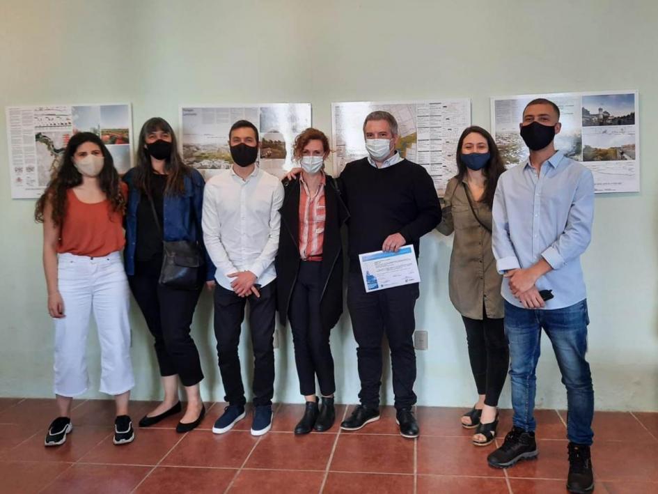 HUE: Equipo ganador del concurso El equipo ganador posando para la foto. Detrás se ven todas las propuestas presentadas