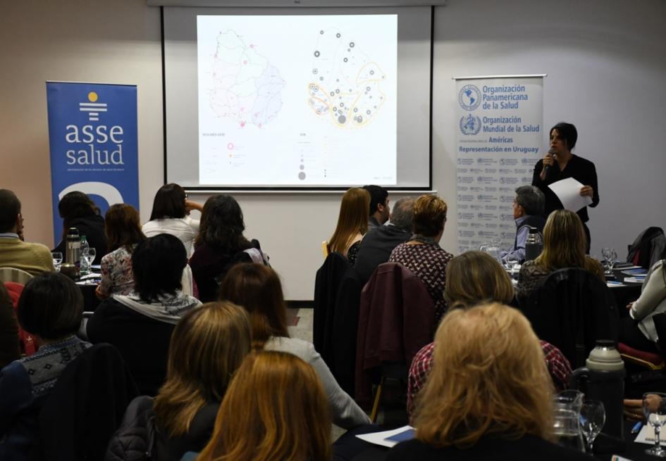 Conversatorio "Fortalecimiento de regionalización en Asse. Desafíos y perspectivas" Se ve una técnica del Mvotma haciendo su presentación, pantalla gigante con varios mapas y personas sentadas en mesas circulares de espaldas mirando hacia la técnica que habla
