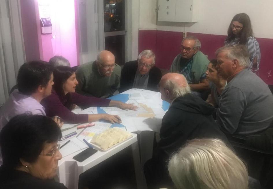 Grupo de personas alrededor de una mesa con mapas dialogan
