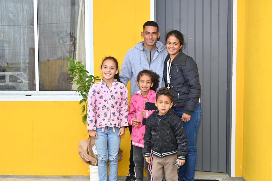 familia beneficiaria Familia parada frente a la casa que recibieron