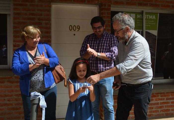 Niña junto a sus padres recibiendo la llave