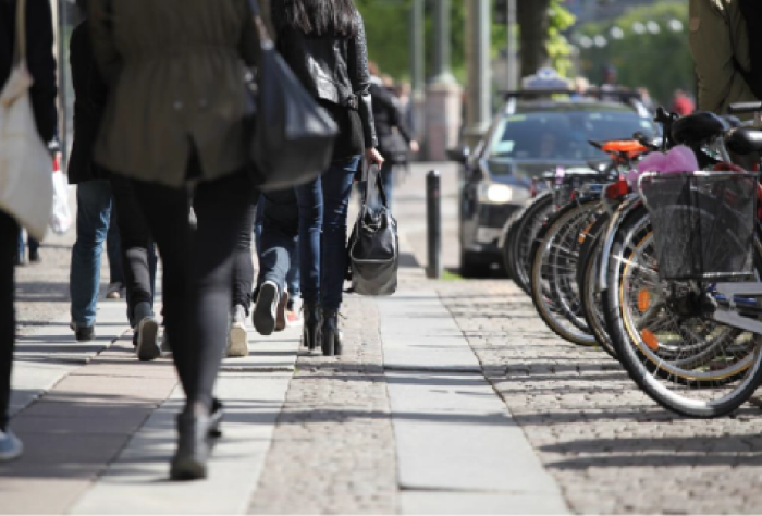 personas caminando y bicicletas estacionadas al costado