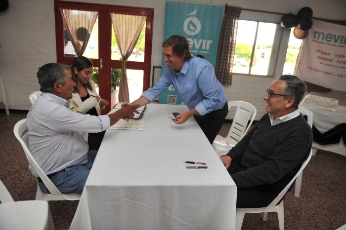 Presidente de Mevir dándole la mano a beneficiario de Colonia en el acto de escrituración
